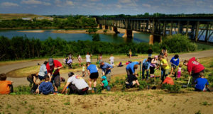 People planting trees, with train tracks in the background.