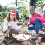 http://Two%20young%20girls%20holding%20a%20newly%20planted%20tree.