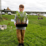 http://Young%20boy%20holding%20seedlings%20to%20the%20planting%20site.