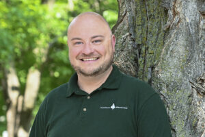 Staff member in front of tree scape