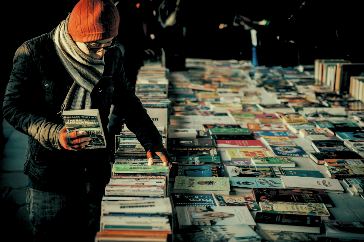 Man with glasses looking through books on sale