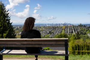 woman sitting on bench looking out over urban green city